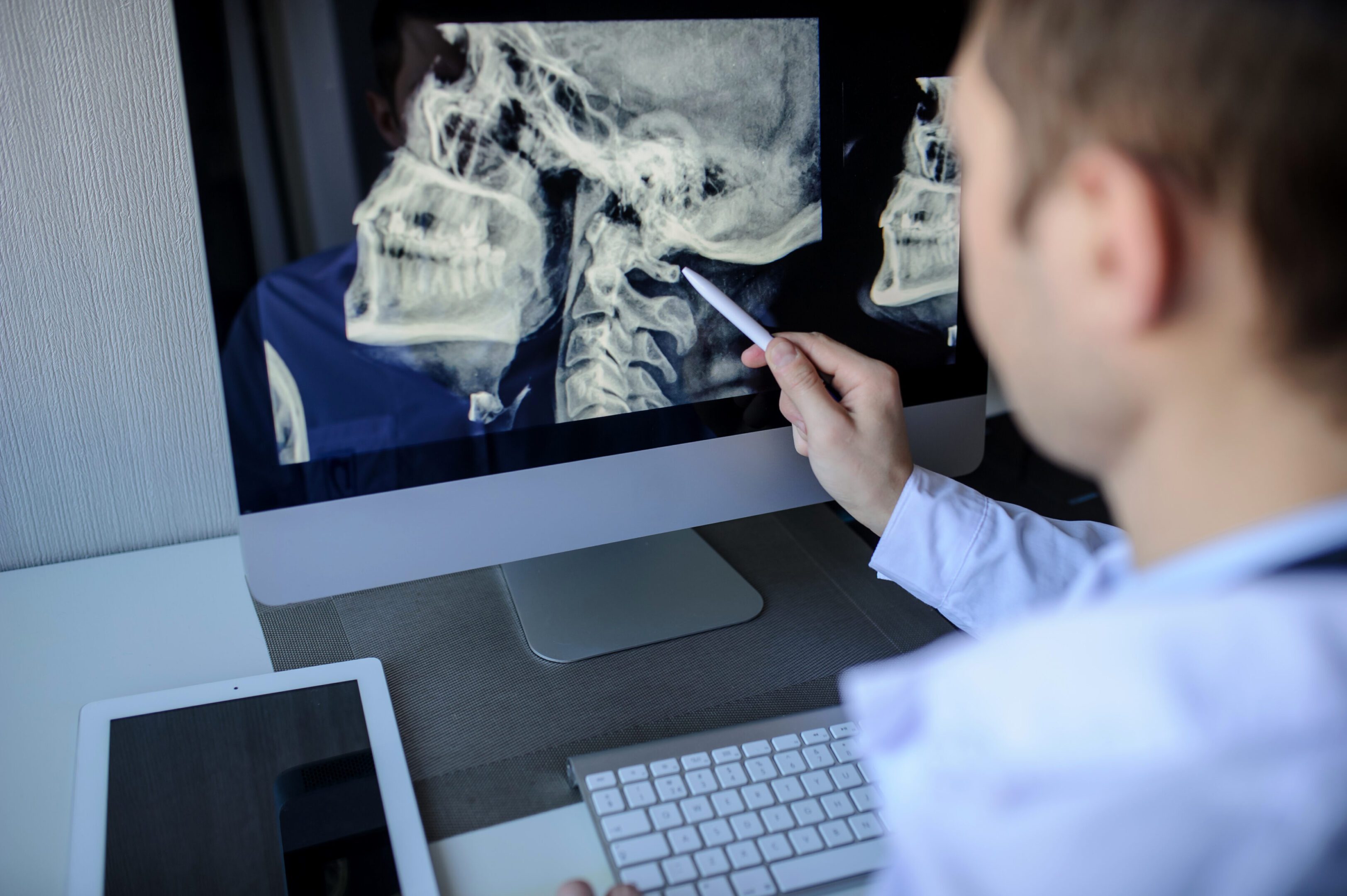 male radiologist examining x-rays on computer Doctor examining neck X-ray on computer screen.